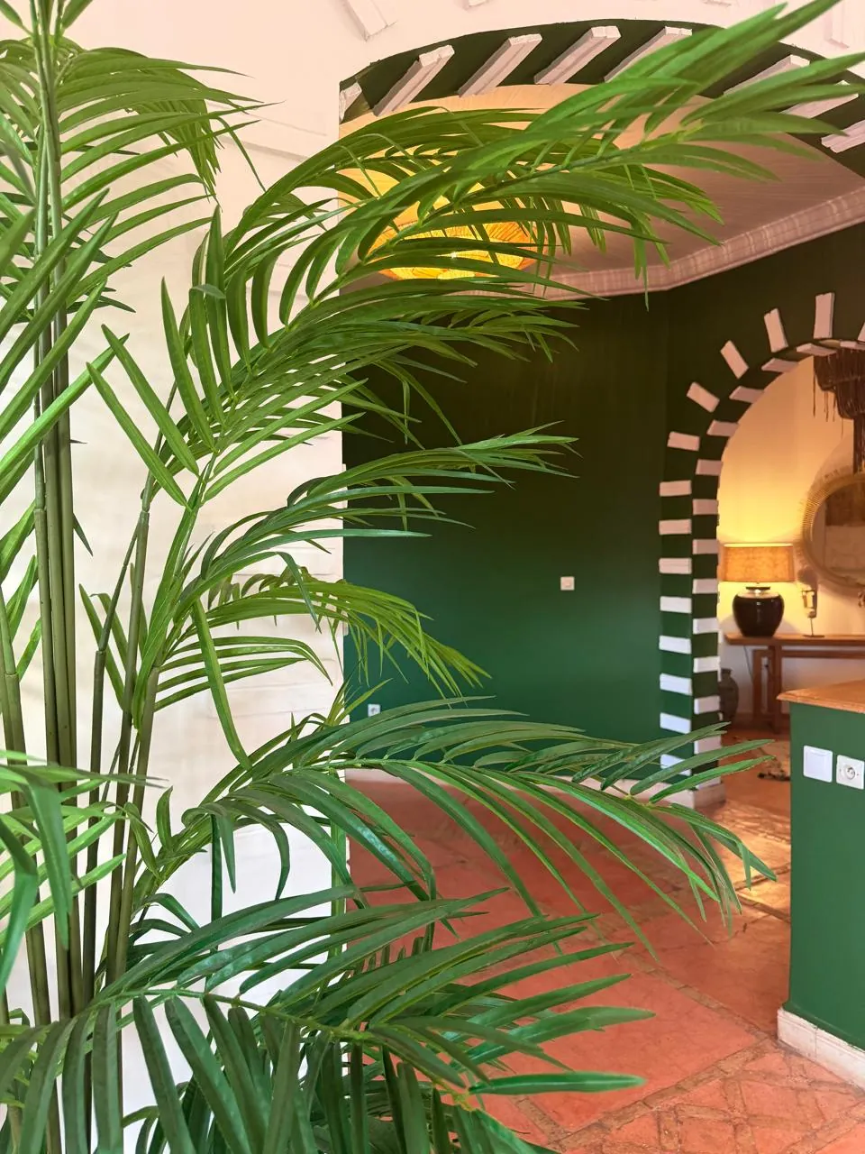 Green and white decorated arch seen through palm leaves